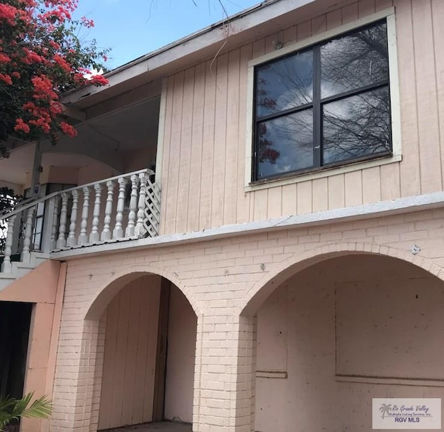 view of side of property featuring a balcony and brick siding