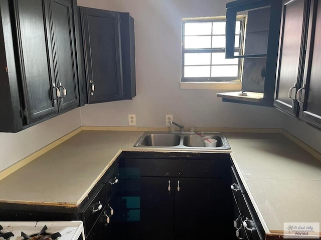 kitchen with a sink, dark cabinets, and light countertops