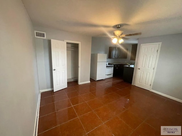 kitchen featuring visible vents, baseboards, ceiling fan, dark tile patterned floors, and white appliances