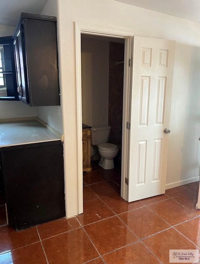 bathroom with baseboards, toilet, and tile patterned flooring