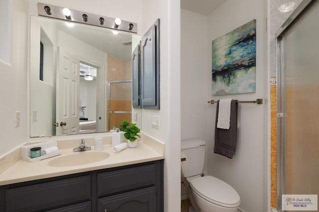 bathroom with toilet, an enclosed shower, and vanity