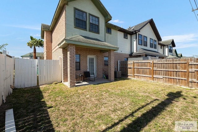 back of property featuring central air condition unit, a fenced backyard, a lawn, and brick siding