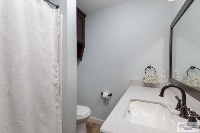 1409 Pine Ct, Harlingen, TX 78550 - bathroom featuring toilet, vanity, wood finished floors, curtained shower, and baseboards