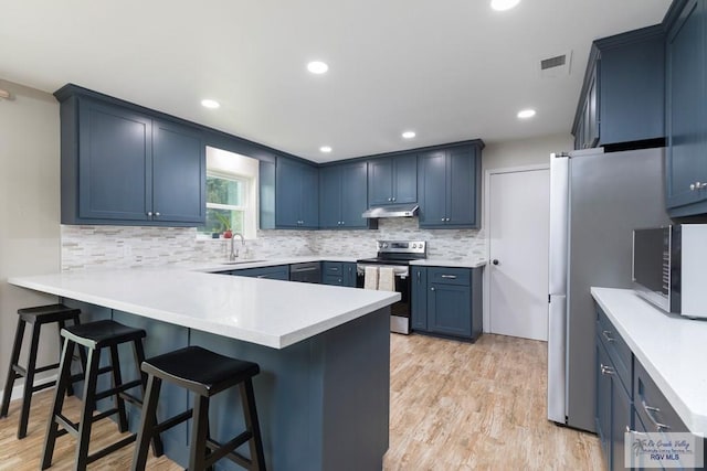 1409 Pine Ct, Harlingen, TX 78550 - kitchen featuring stainless steel appliances, a peninsula, backsplash, a kitchen breakfast bar, and recessed lighting