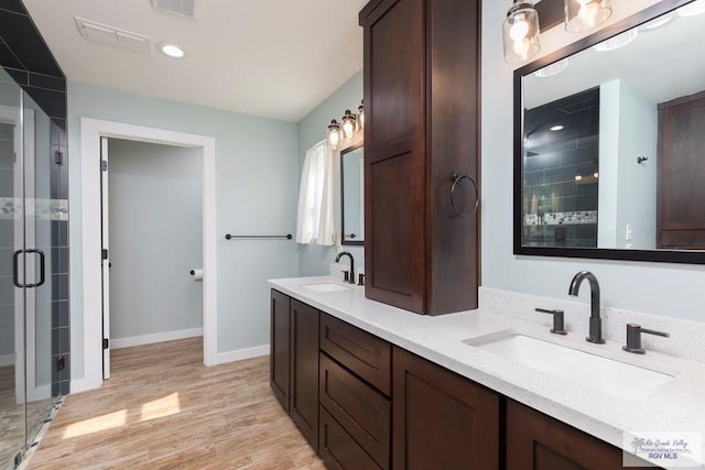 1409 Pine Ct, Harlingen, TX 78550 - full bath with double vanity, a shower stall, wood finished floors, baseboards, and recessed lighting