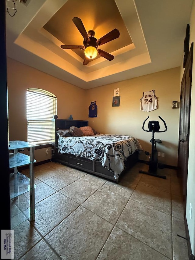 bedroom with a raised ceiling and ceiling fan