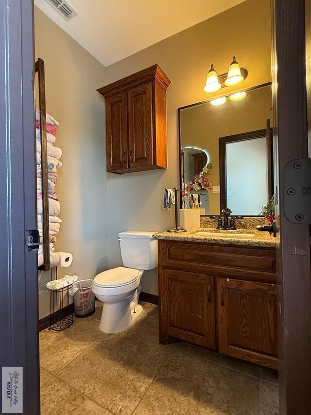 half bathroom with visible vents, toilet, vanity, and baseboards