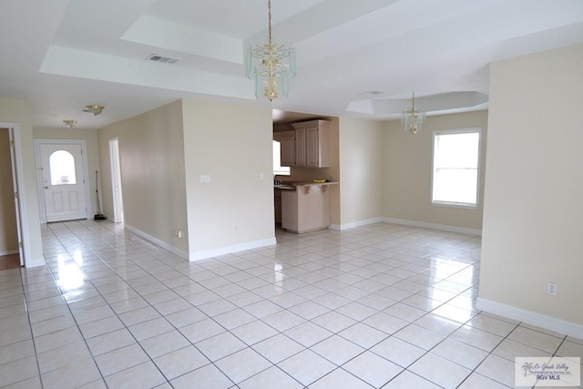 487 Agua Viva Ln, Brownsville, TX 78521 - unfurnished living room with a raised ceiling, a chandelier, light tile patterned floors, and healthy amount of natural light