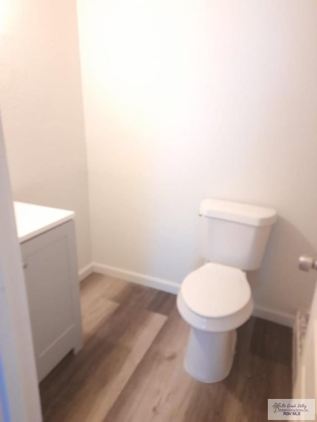 bathroom featuring baseboards, vanity, toilet, and wood finished floors