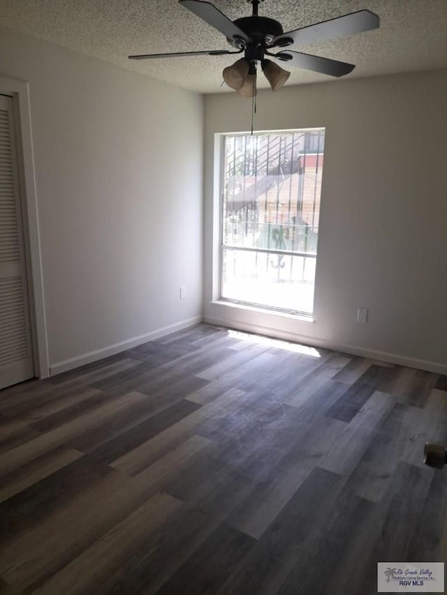 unfurnished room featuring a textured ceiling, wood finished floors, and baseboards