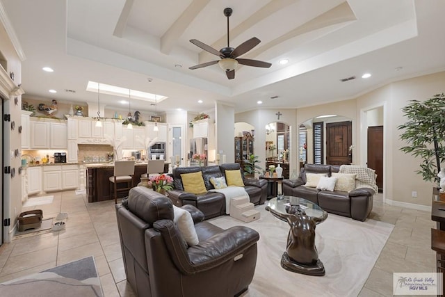 living room with ceiling fan, light tile patterned flooring, and a tray ceiling