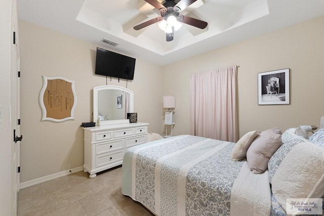 bedroom featuring ceiling fan, a raised ceiling, and light tile patterned floors