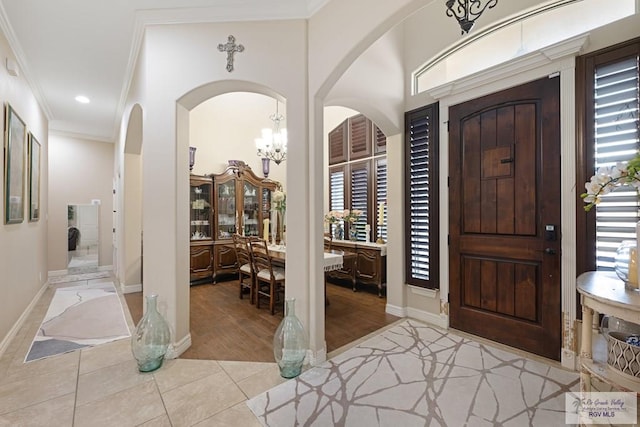 entryway with a healthy amount of sunlight, crown molding, and light hardwood / wood-style flooring