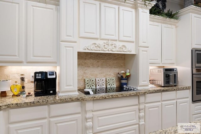 kitchen featuring white cabinets, appliances with stainless steel finishes, decorative backsplash, and light stone counters