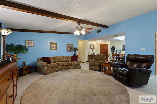 living room featuring ceiling fan, a textured ceiling, light tile patterned floors, and beamed ceiling