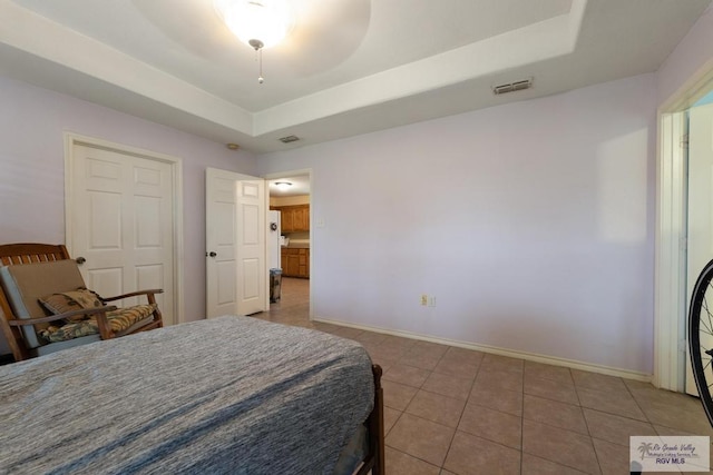 tiled bedroom with ceiling fan and a raised ceiling