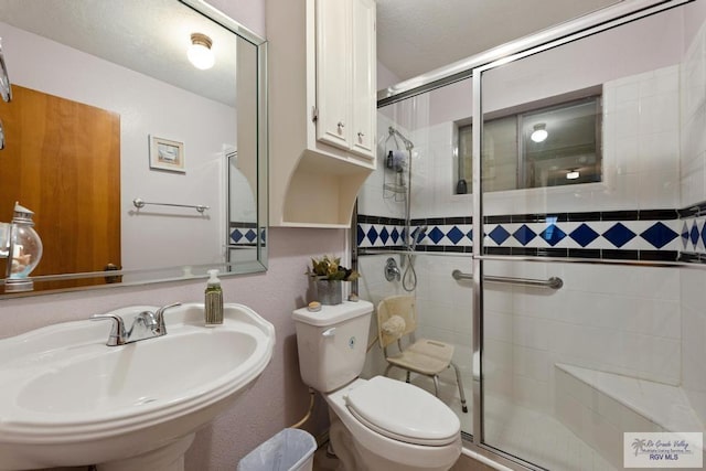 bathroom with sink, toilet, and an enclosed shower