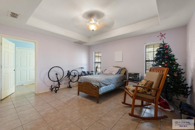 bedroom featuring a raised ceiling, light tile patterned floors, and ceiling fan