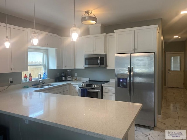 kitchen featuring stainless steel appliances, marble finish floor, white cabinets, a sink, and a peninsula