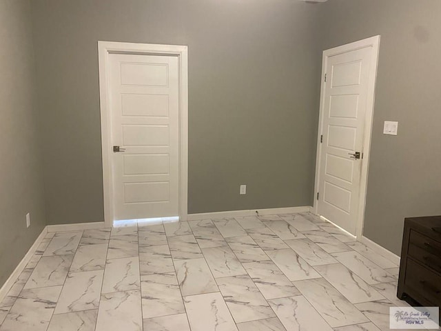 unfurnished room featuring baseboards and marble finish floor