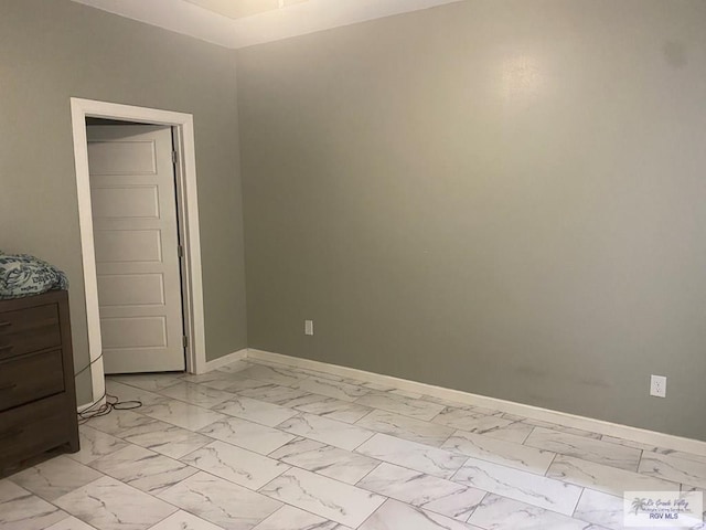 unfurnished room with baseboards and marble finish floor