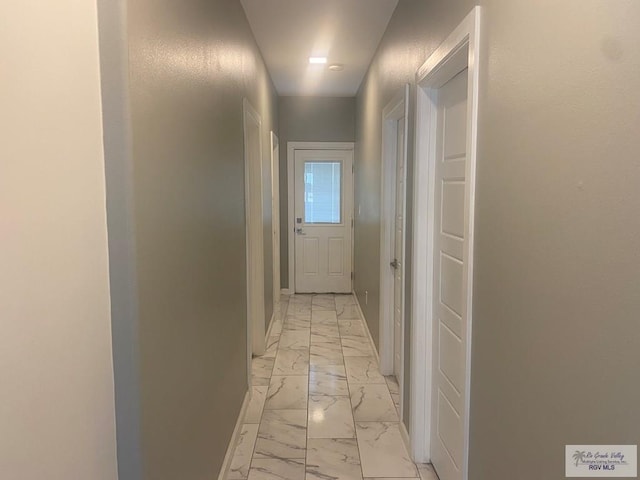 hallway featuring marble finish floor and baseboards