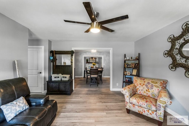 living room featuring ceiling fan, baseboards, and wood finished floors