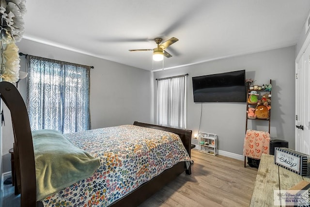 bedroom featuring multiple windows, wood finished floors, a ceiling fan, and baseboards