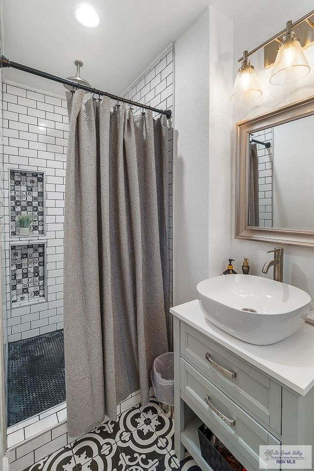 bathroom with tiled shower, vanity, and tile patterned floors