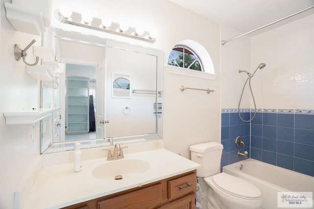 full bathroom featuring vanity, tiled shower / bath, and toilet