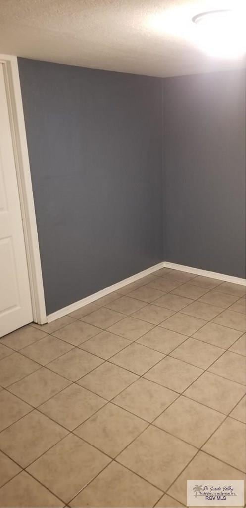 empty room featuring a textured ceiling and baseboards