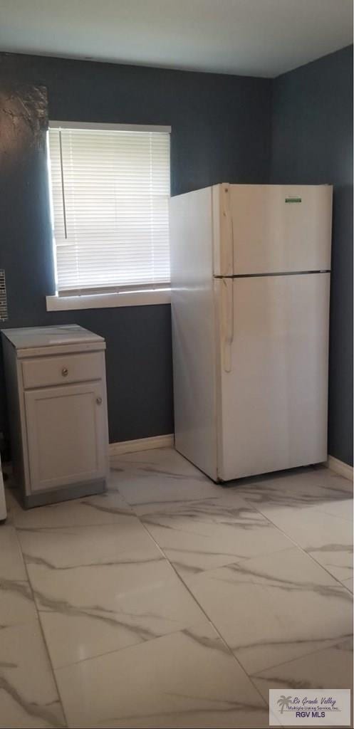 kitchen featuring marble finish floor and freestanding refrigerator