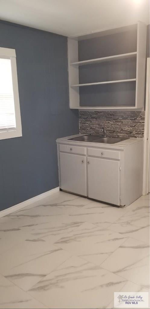 interior space with marble finish floor, baseboards, and a sink