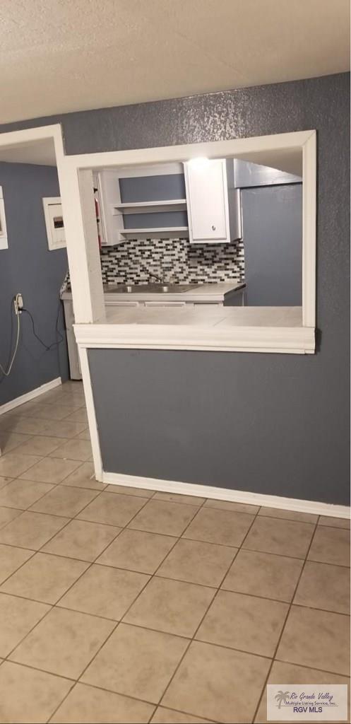 kitchen featuring light tile patterned floors, white cabinets, decorative backsplash, and light countertops