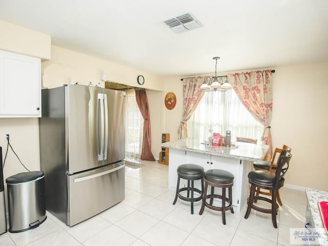 3104 Buckingham Ct, Brownsville, TX 78526 - kitchen featuring freestanding refrigerator, plenty of natural light, a breakfast bar area, and white cabinetry