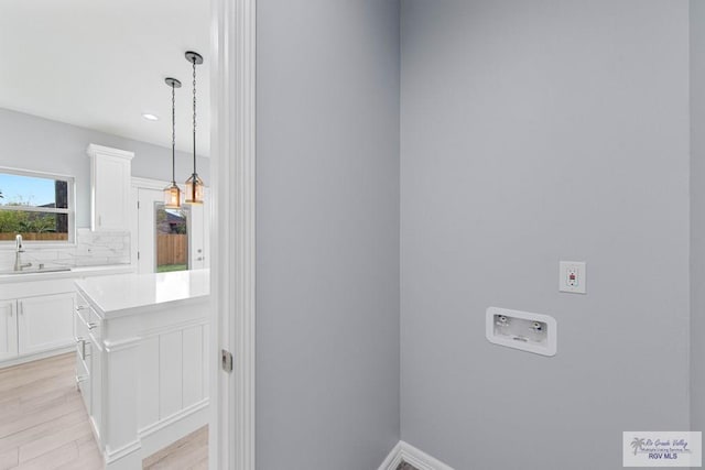 washroom featuring hookup for a washing machine, light hardwood / wood-style floors, and sink