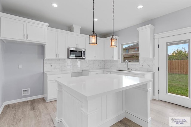 kitchen with white cabinets, sink, tasteful backsplash, decorative light fixtures, and a kitchen island