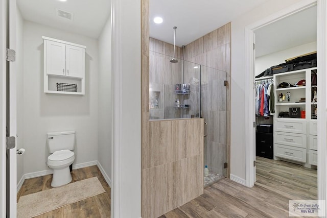 bathroom with toilet, wood-type flooring, and walk in shower