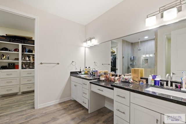 bathroom featuring hardwood / wood-style floors, vanity, and tiled shower