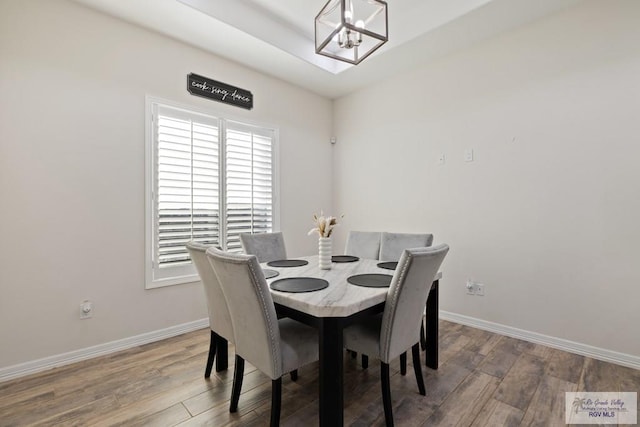 dining area with hardwood / wood-style flooring and an inviting chandelier