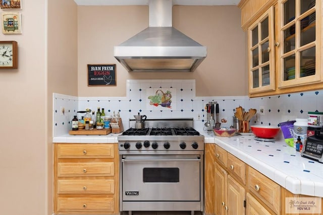 kitchen featuring extractor fan, tile countertops, backsplash, and designer stove