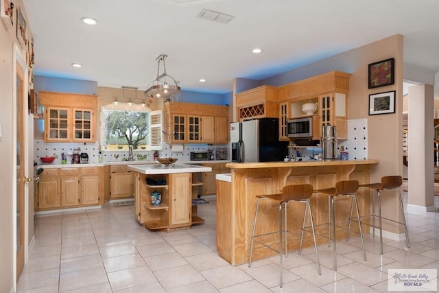 kitchen featuring appliances with stainless steel finishes, a center island, a breakfast bar, and decorative backsplash