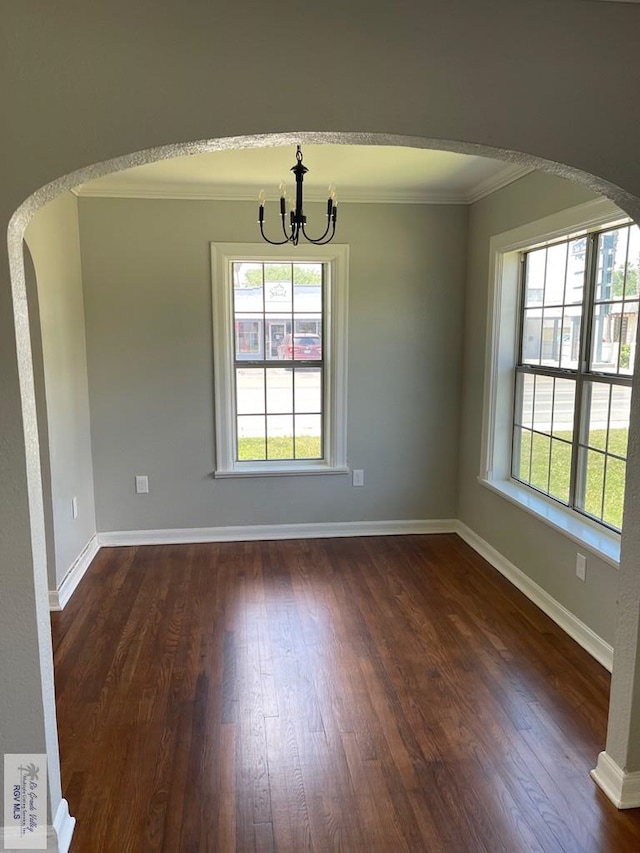 unfurnished dining area featuring a notable chandelier, crown molding, and dark wood-type flooring