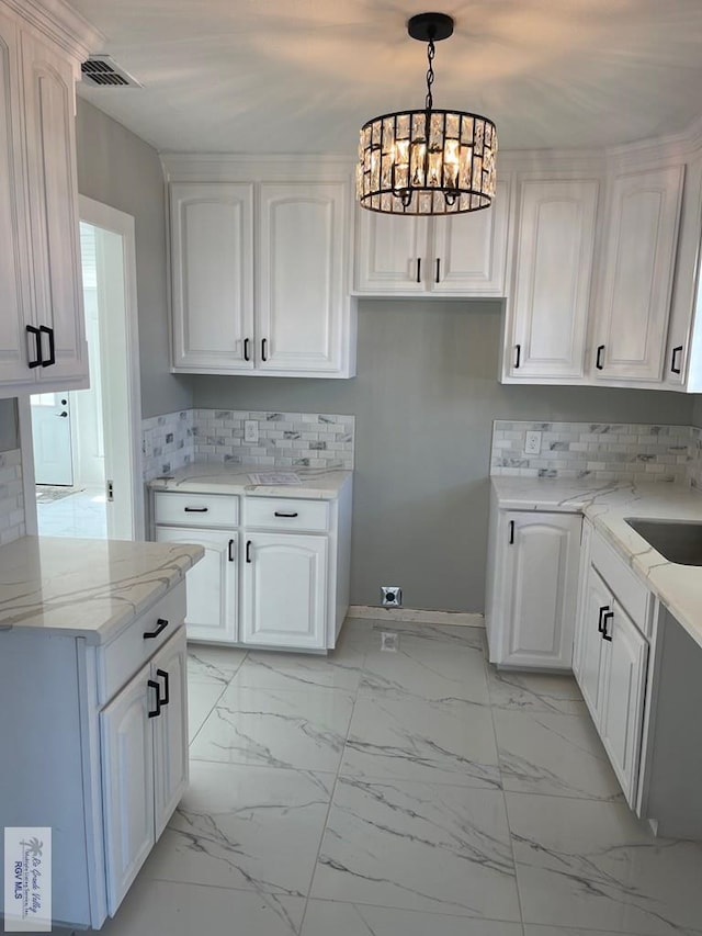 kitchen featuring white cabinetry, sink, a notable chandelier, pendant lighting, and decorative backsplash