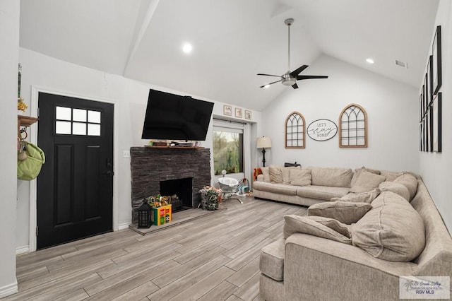 living room with ceiling fan, high vaulted ceiling, a fireplace, and light hardwood / wood-style floors