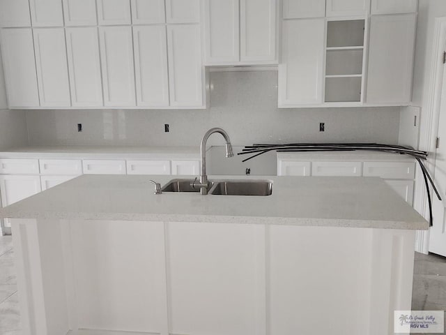 kitchen with white cabinets, sink, and an island with sink