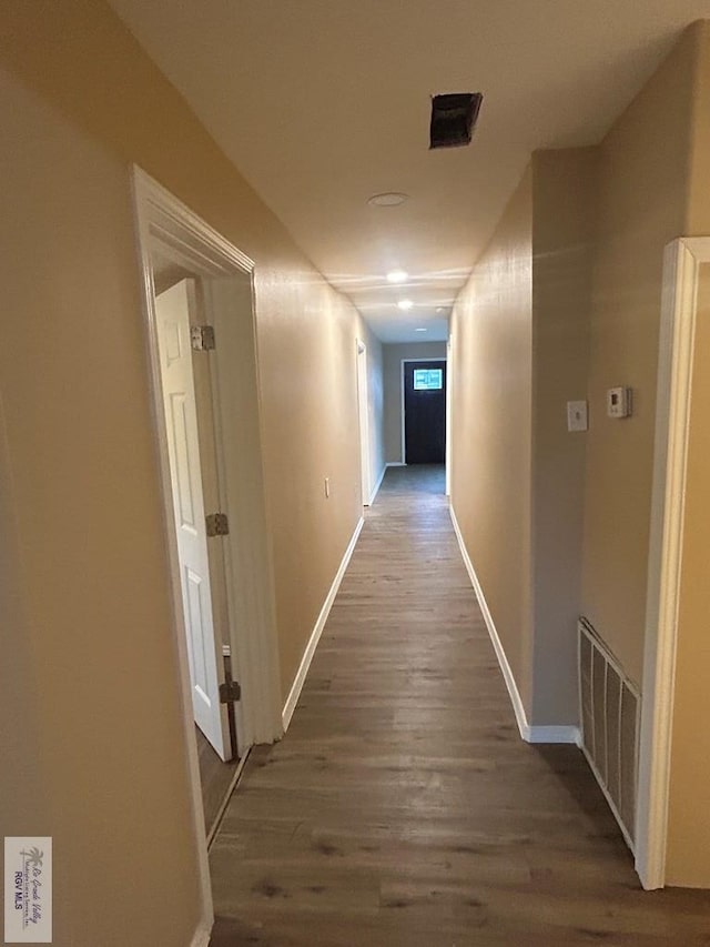 hallway featuring dark wood-style flooring, visible vents, and baseboards