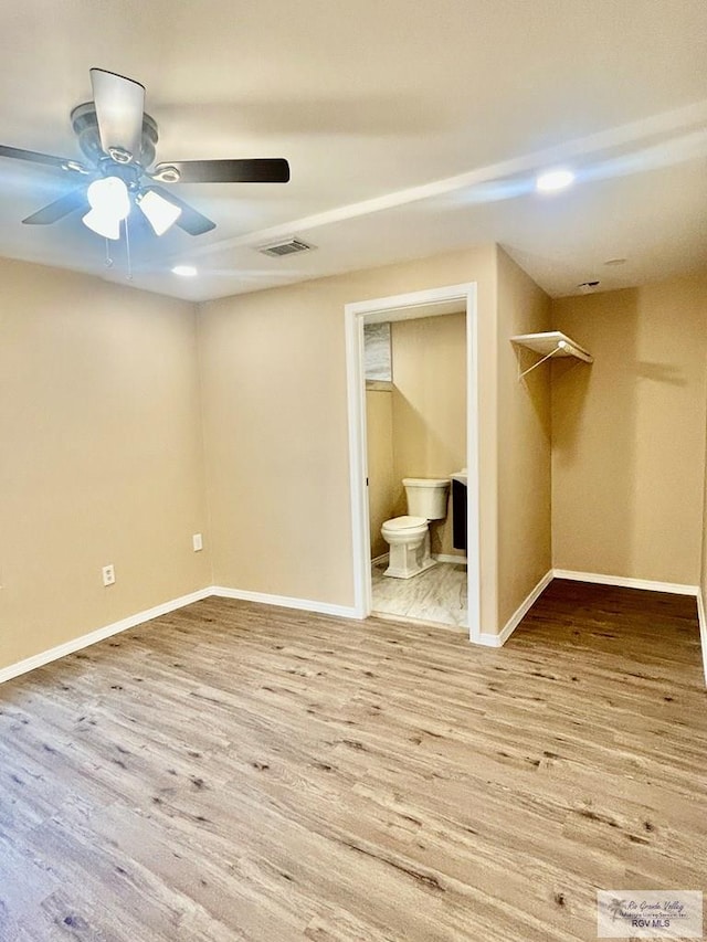 unfurnished bedroom with visible vents, baseboards, ceiling fan, wood finished floors, and ensuite bathroom