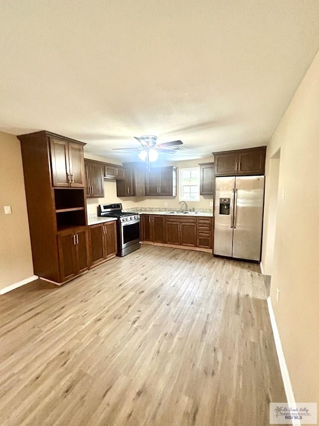 kitchen with stainless steel appliances, light wood-type flooring, light countertops, and a sink