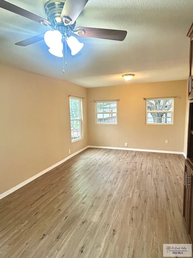 unfurnished room with ceiling fan, light wood-style flooring, and baseboards